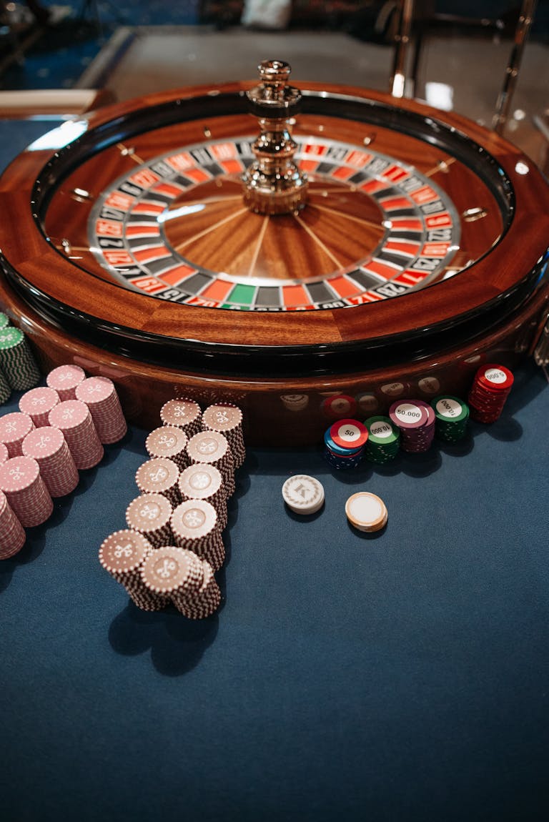 Roulette wheel on table with neatly stacked poker chips, capturing the essence of a casino.
